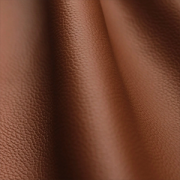 Close-up of brown biotechnology-engineered material featuring a smooth leather-inspired texture and soft folds.
