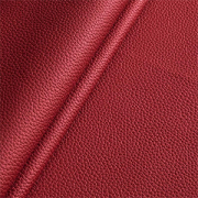 Close-up of red bio-based performance material with a refined leather-like grain and folded texture surface.